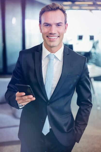 Portrait of happy businessman looking at mobile phone in office