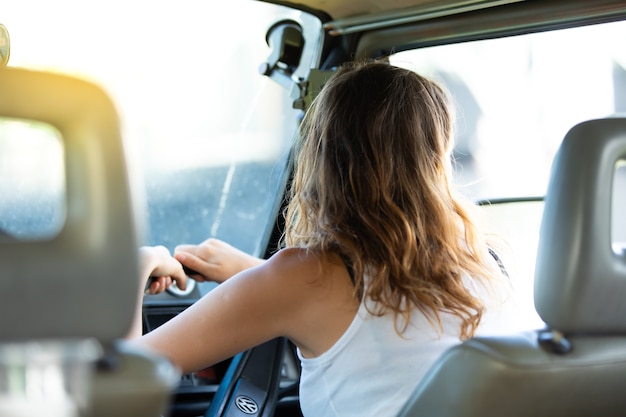 Portrait happy caucasian woman drives a old vintage camper van on road.