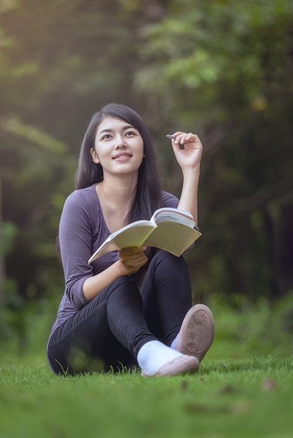 Portrait of happy charming  Asian woman reading a book outdoors