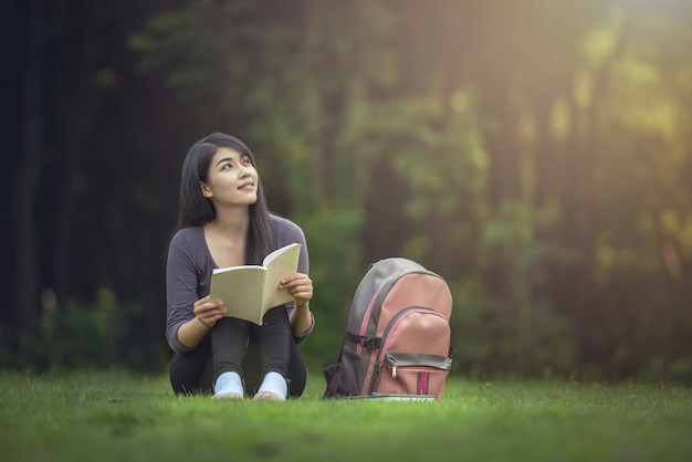 Portrait of happy charming  Asian woman reading a book outdoors