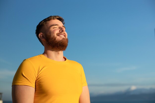 Portrait of happy cheerful positive guy young handsome bearded man with beard is enjoying sunny day