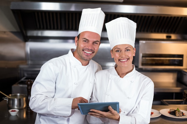 Portrait of happy chefs holding clipboard in kitchen