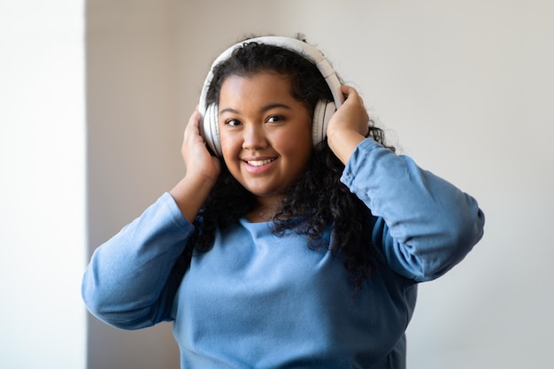 Portrait of happy chubby woman listening to music at home