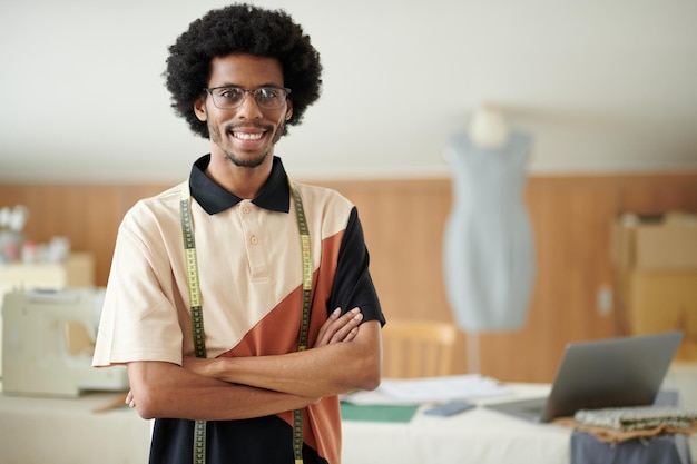 Portrait of happy confident fashion designer standing in his atelier