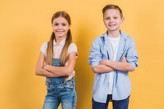 Portrait of a happy cute boy and girl with their arms crossed looking to camera