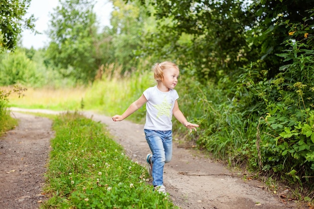 Portrait of happy cute little girl outdoor Kid playing running in park or garden