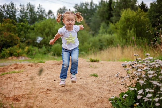 Portrait of happy cute little girl outdoor palying in park, garden, meadow