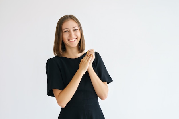 Portrait of a happy cute woman in a black dress on a white background smiling