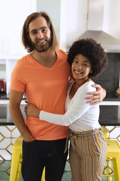 Portrait of happy diverse couple in kitchen smiling and embracing