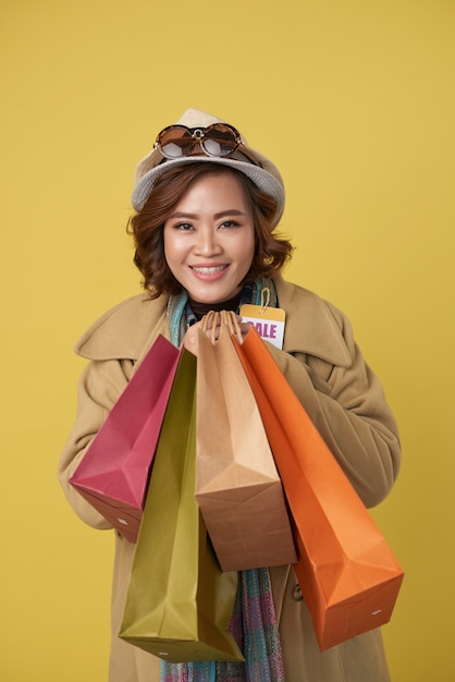 Portrait of happy exited young woman holding many paper bags with clothes she bought on sale