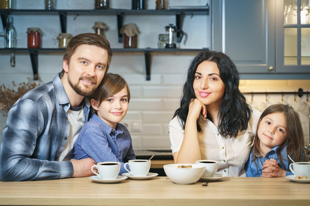 Portrait of a happy family drinking tea with cookies in the kitchen.