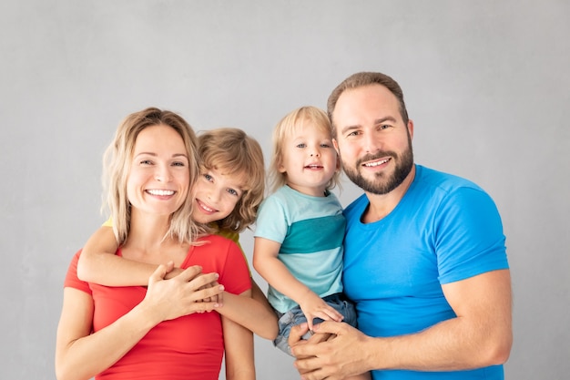 Portrait of happy family - father, mother, daughter and son - against grey surface