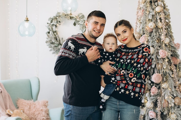 Portrait of happy family of father mother and little curly son celebrating Christmas together at home New Years Eve concept