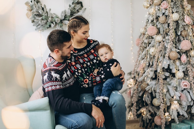 Portrait of happy family of father mother and little curly son celebrating Christmas together at home New Years Eve concept