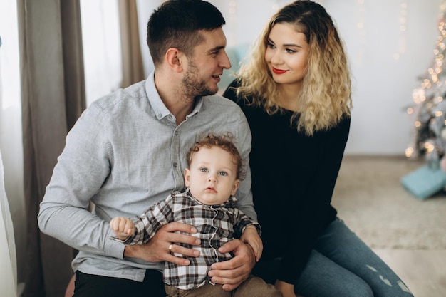 Portrait of happy family of father mother and little curly son celebrating Christmas together at home New Years Eve concept