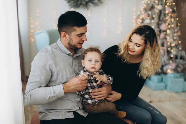 Portrait of happy family of father mother and little curly son celebrating Christmas together at home New Years Eve concept