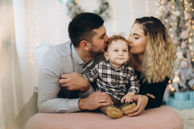 Portrait of happy family of father mother and little curly son celebrating Christmas together at home New Years Eve concept