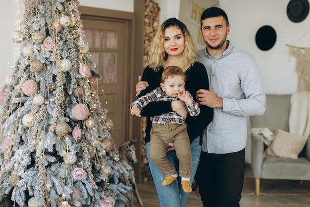 Portrait of happy family of father mother and little curly son celebrating Christmas together at home New Years Eve concept