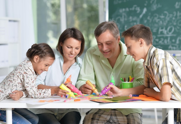 Portrait of happy family of four drawing together at home