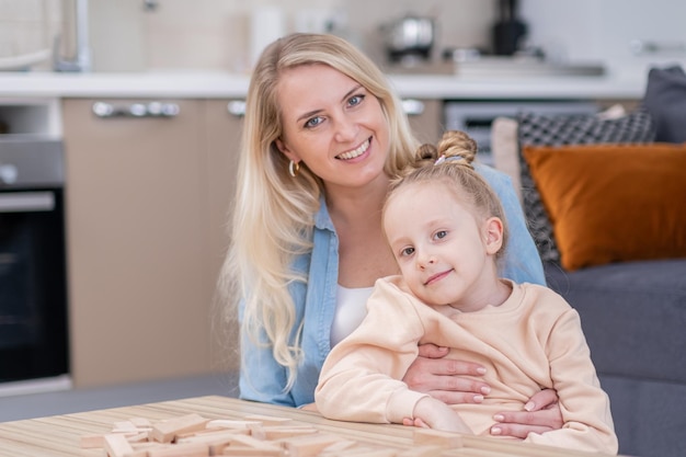 Portrait of happy family mother andkid girl in casual clohes smiling hugging and looking at camera