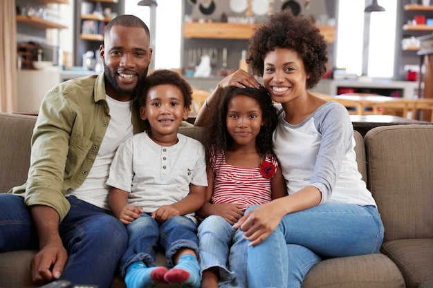 Portrait Of Happy Family Sitting On Sofa In Open Plan Lounge