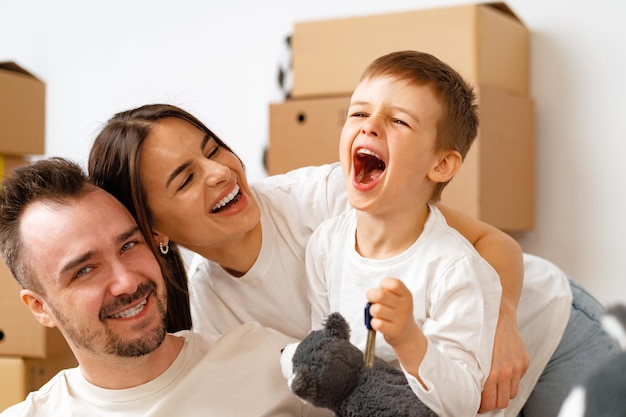 Portrait of happy family with cardboard boxes in new house at moving day