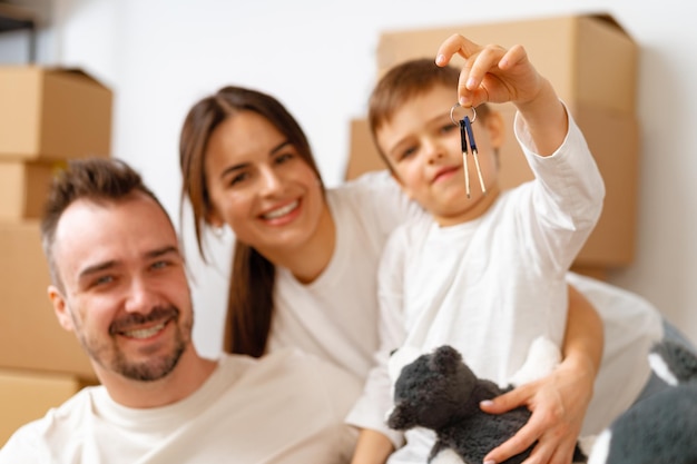 Portrait of happy family with cardboard boxes in new house at moving day