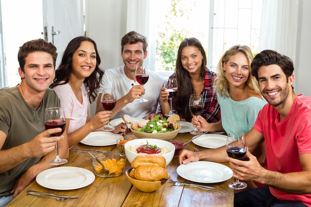 Portrait of happy friends holding wine glasses while having lunch