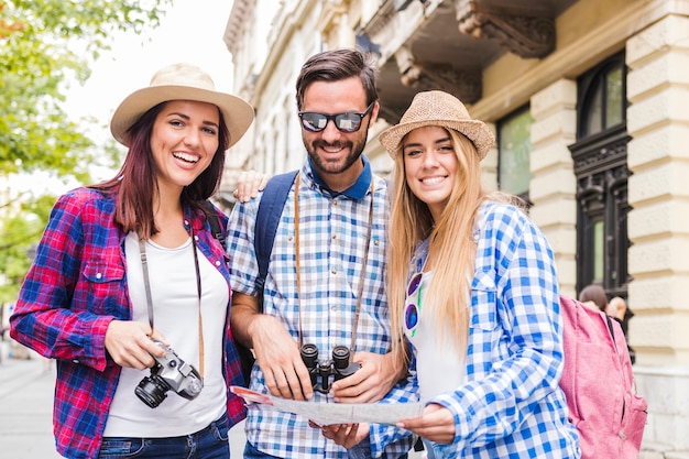 Portrait of happy friends with map at outdoors