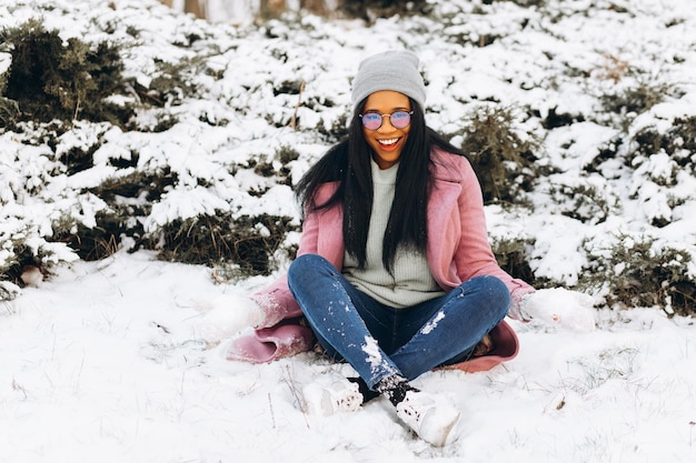 Portrait of happy girl African American young woman in glasses and gloves is smiling at winter