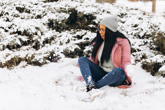 Portrait of happy girl African American young woman in glasses and gloves is smiling at winter