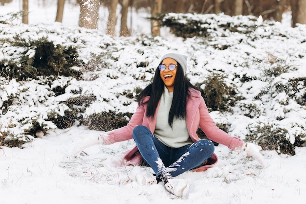 Portrait of happy girl African American young woman in glasses and gloves is smiling at winter