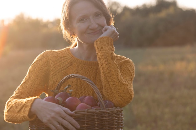 Portrait happy girl holds  basket  with juicy apples in the garden. aesthetics of rural life