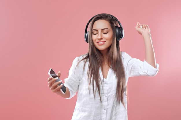 Portrait of a happy girl listening music with wireless headphones from a smartphone