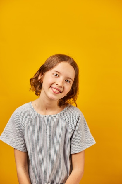 Portrait happy girl teenage in yellow studio background positive emotions lifestyle