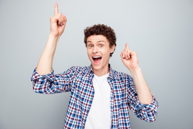 Portrait of happy guy dance raise index fingers up isolated on gray