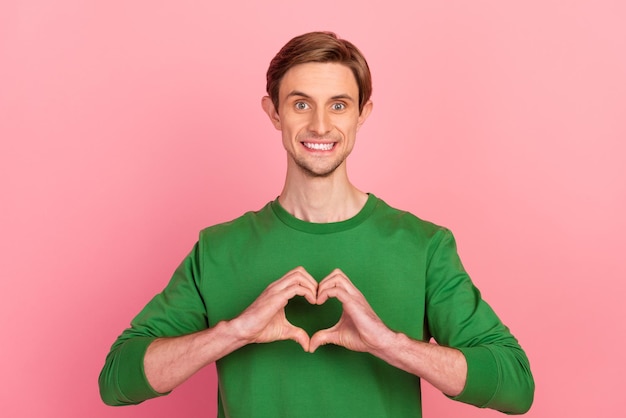 Portrait of happy handsome man imaking heart with fingers wear sweater jumper isolated pastel color background