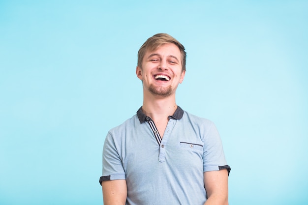 Portrait of happy handsome man laughing on blue