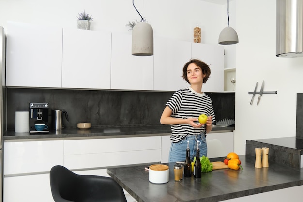 Photo portrait of happy healthy young woman vegetarian making herself salad posing near vegetables on