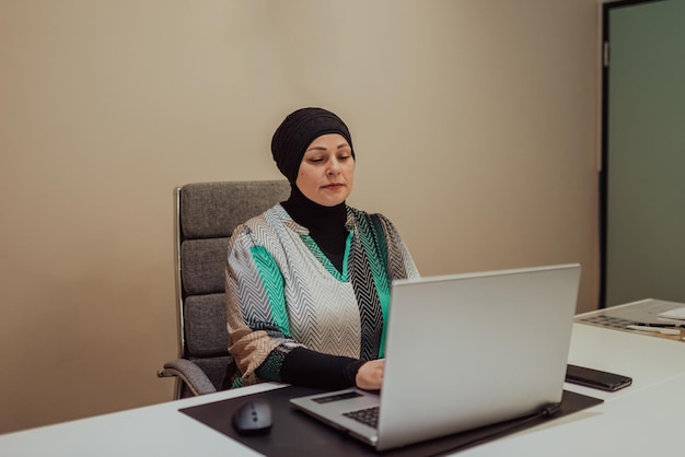 Portrait of a happy hijab muslim manager at bright office. Smiling at camera while sitting at office desk.High quality photo.