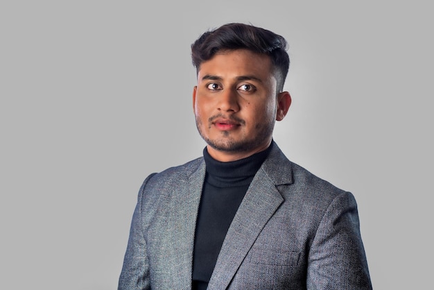 Portrait of Happy Indian young man businessman wearing a blazer on grey background posing satisfied successful male in formal suit