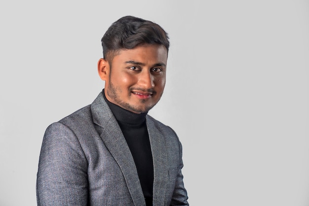 Portrait of Happy Indian young man businessman wearing a blazer on grey background posing satisfied successful male in formal suit