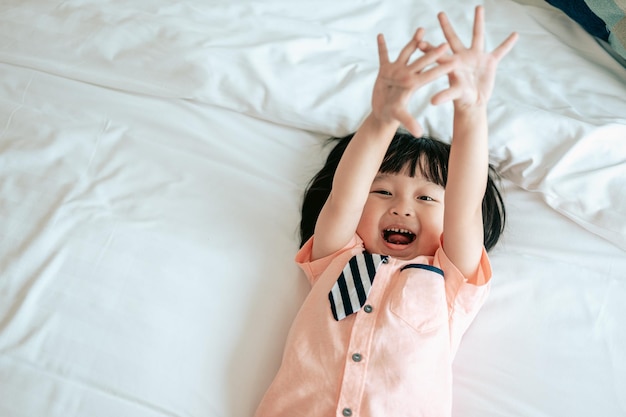 Portrait of happy little boy cheerful in white bedroom Little boy is happiness on the bedHappy family lifestyle concept