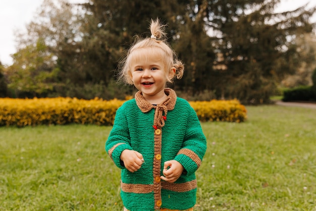 Portrait of a happy little girl in autumn clothes. the child laughs against the background of nature.