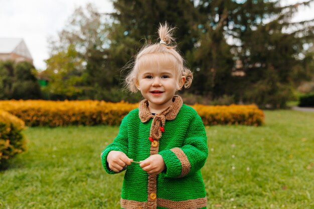 Portrait of a happy little girl in autumn clothes. the child laughs against the background of nature.