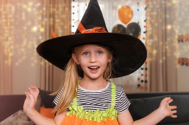 Portrait of a happy little girl dressed as a witch for Halloween home party