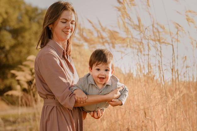 Portrait of happy loving mother hugging her baby son in the sunny park