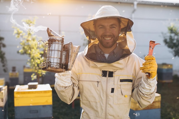 Portrait of a happy male beekeeper working in an apiary near beehives with bees Collect honey Beekeeper on apiary Beekeeping concept