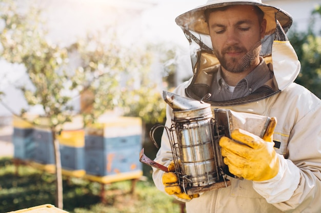 Portrait of a happy male beekeeper working in an apiary near beehives with bees Collect honey Beekeeper on apiary Beekeeping concept