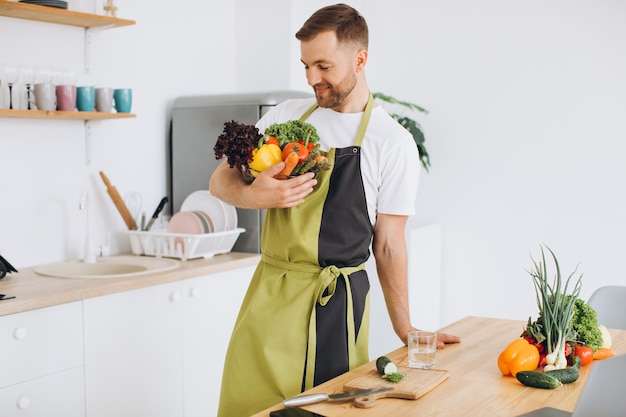 Portrait of a happy man holding a plate of fresh vegetables in the kitchen